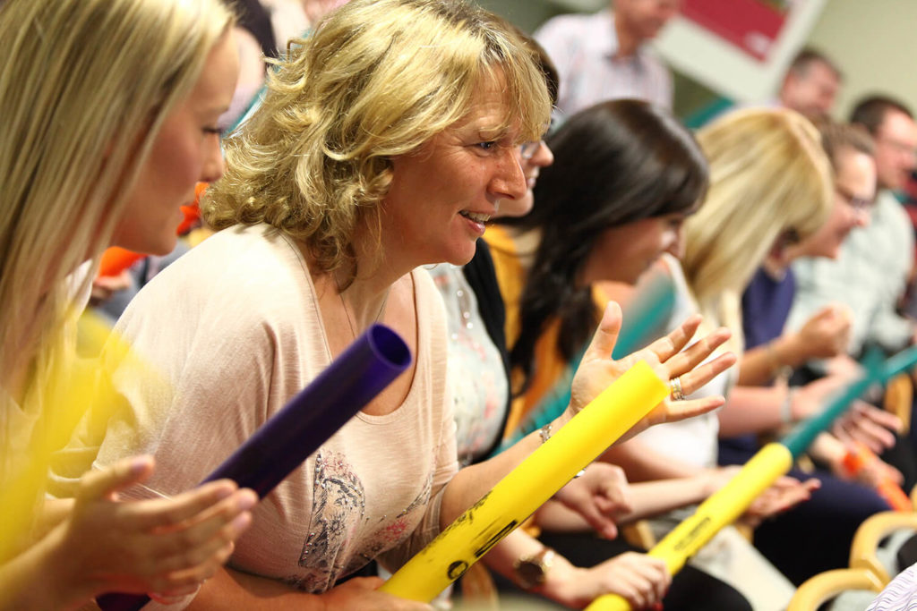 Women using boomwhackers at a conference ice breaker