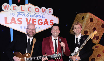 Rock n Roll band in front of a Las Vegas sign at a corporate event