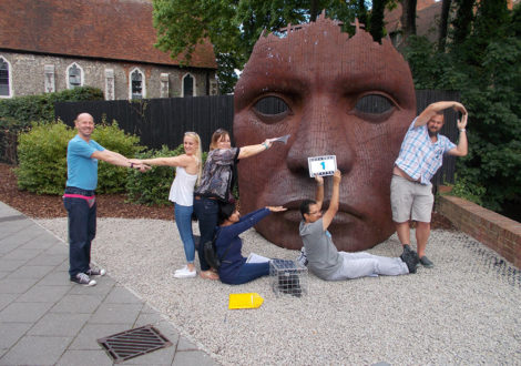 Team spelling help in front of giant mask in Spy Catcher team building event