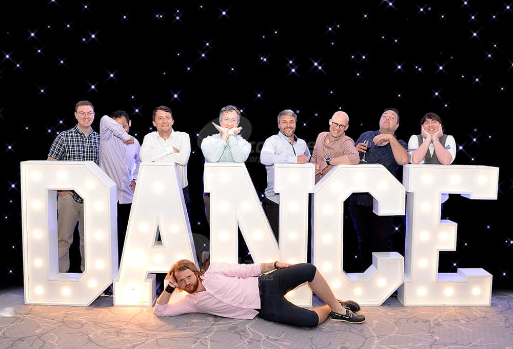Group posing around Dance sign at company party