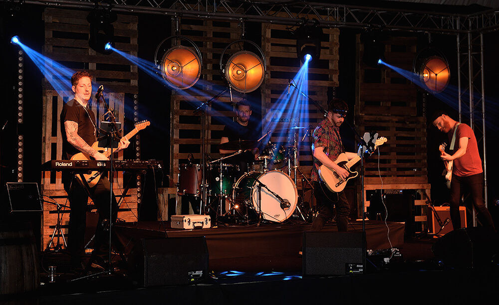 Band performing on stage with lights shining at company party event