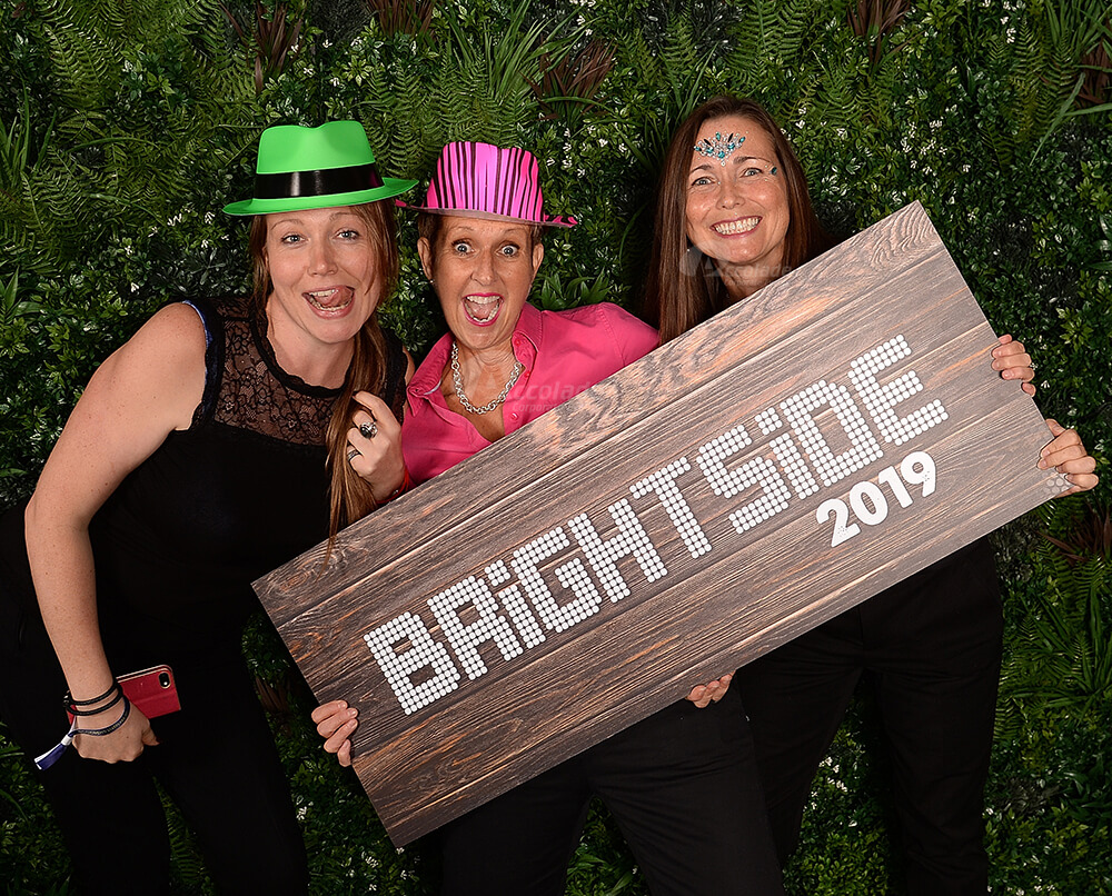 Three women posing in photo area at indoor festival corporate event