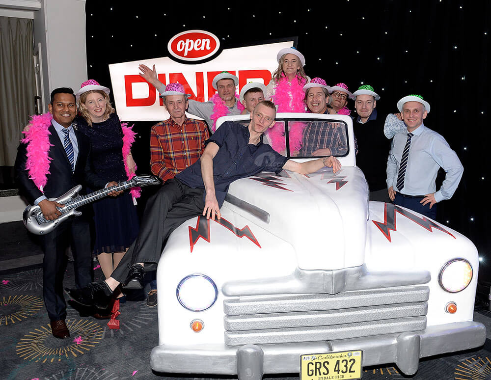 People posing around Cadillac car at company event
